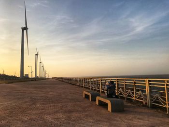 Couple embracing on bridge over sea at sunset