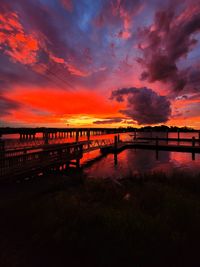 Silhouette bridge over river against sky during sunset