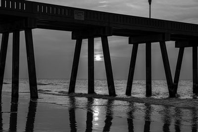 Reflection of bridge in sea against sky