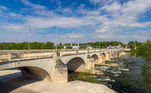 Arch bridge over river against sky in city