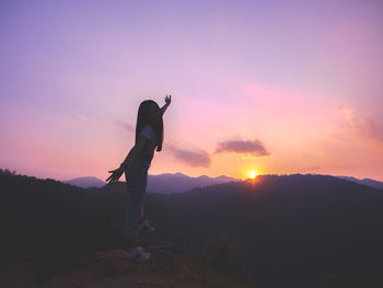 Silhouette man standing on land against sky during sunset