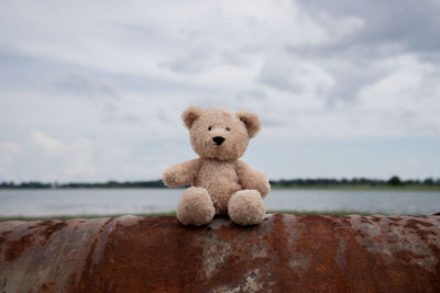 Close-up of stuffed toy on rock against sky