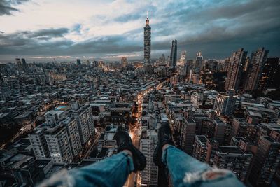 Low section of person over cityscape against sky