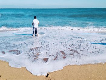 Rear view of man relaxing on beach