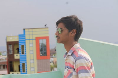 Man standing on building terrace against sky
