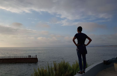 Rear view of man looking at sea against sky