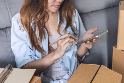 Midsection of woman using mobile phone while sitting on laptop