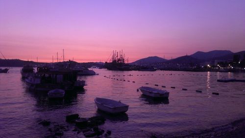 Boats moored in sea at sunset