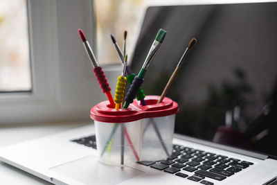 Close-up of paintbrushes in container on laptop