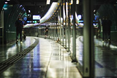 People walking on illuminated walkway at night