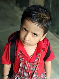 Portrait of cute schoolboy standing on footpath