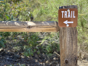 Close-up of sign on wooden post in field