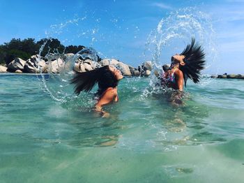 Side view of girls splashing hair while swimming in sea
