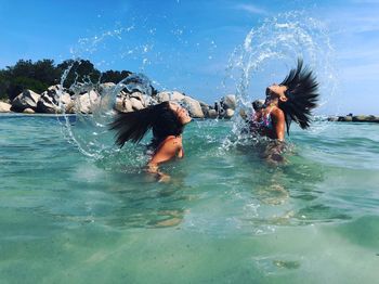 Girls splashing water with hair in sea