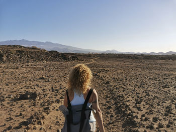 Rear view of woman standing on land against sky