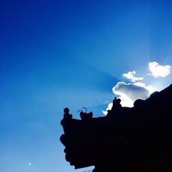 Low angle view of silhouette statue against blue sky