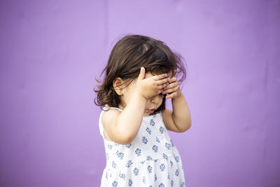 Girl looking away while standing against pink wall