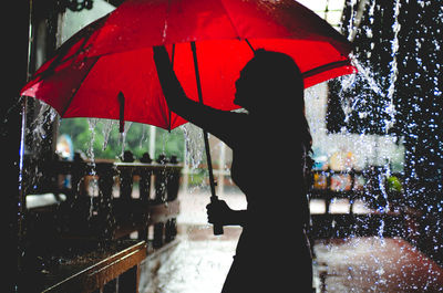 Woman holding red umbrella in the rain