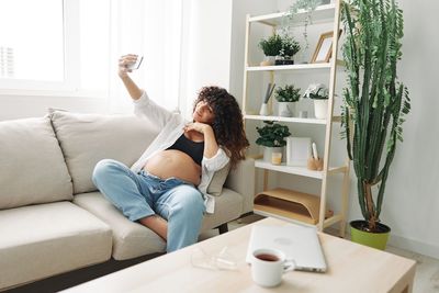 Side view of woman sitting on sofa at home