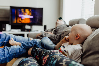 Family relaxing on couch watching tv while dad naps