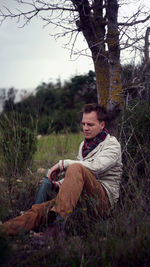 Sad man sitting on field in forest