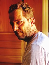 Portrait of mature man standing against wall at home