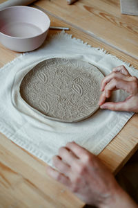 Beautiful raw clay plate with ornament on table in workshop