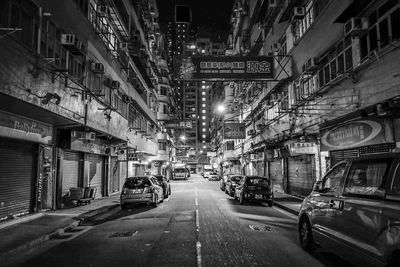 Cars parked on street amidst buildings at night