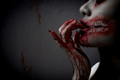 Side view of young woman with halloween make-up against wall