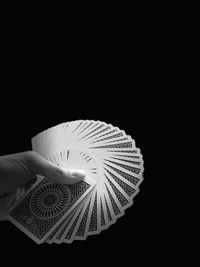 Close-up of hand holding umbrella against black background