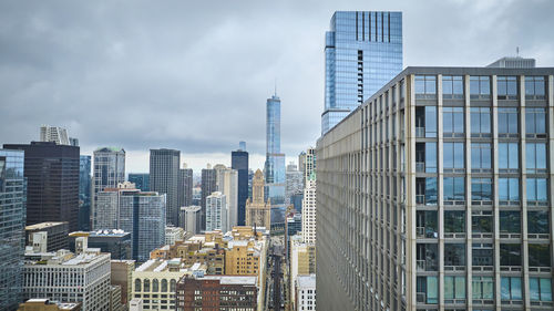 Modern buildings in city against cloudy sky