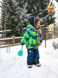 Full length of child on snow covered tree in winter