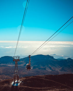 Overhead cable car over mountains against blue sky