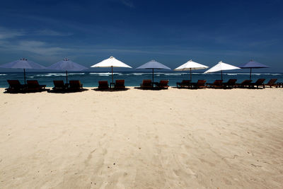 Lounge chairs on beach against sky