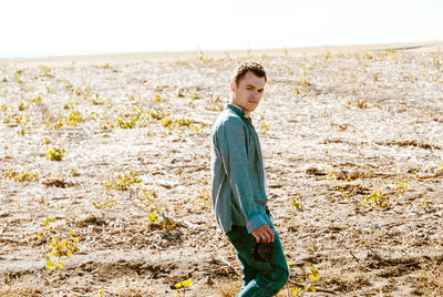 Portrait of young man with camera standing on field