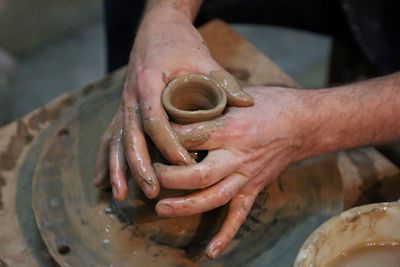 Cropped hands making earthenware pottery wheel at workshop