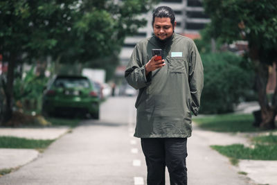 Full length of man using mobile phone on road