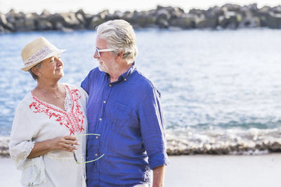 Senior couple looking each other face to face while standing at beach