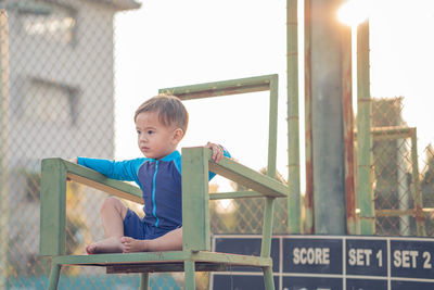 Boy looking away while sitting on seat