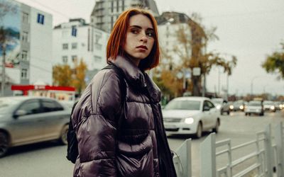 Thoughtful young woman standing by road in city