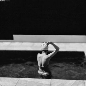 Rear view of woman sitting in swimming pool