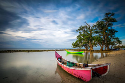 Boat moored on beach against sky