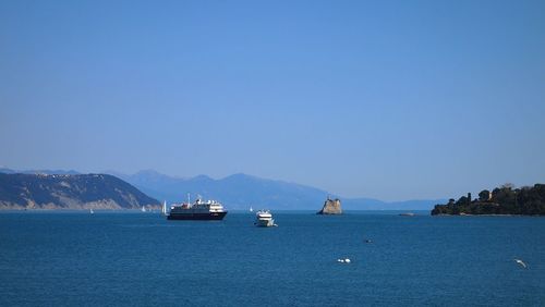 Sailboats in sea against clear blue sky