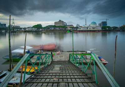 View of boats in river against cloudy sky