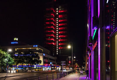 Illuminated street amidst buildings at night