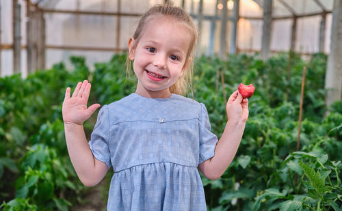 Portrait of smiling young woman standing against plants