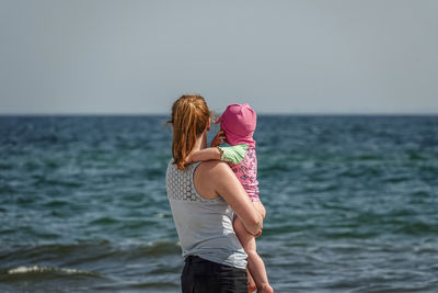 Rear view of woman standing at sea against clear sky