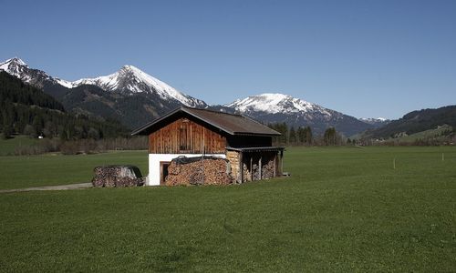 Built structure on field by mountain against sky