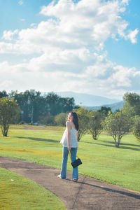 Rear view of woman walking on field against sky