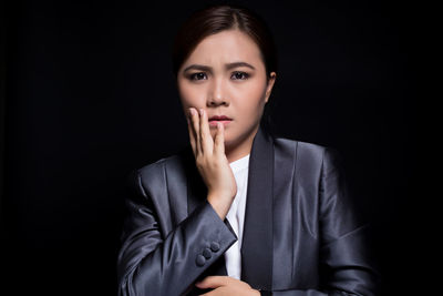 Portrait of worried businesswoman against black background